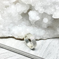 Silver ring on a white stone surface